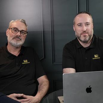 Two InboxArmy team members in branded shirts seated behind a laptop